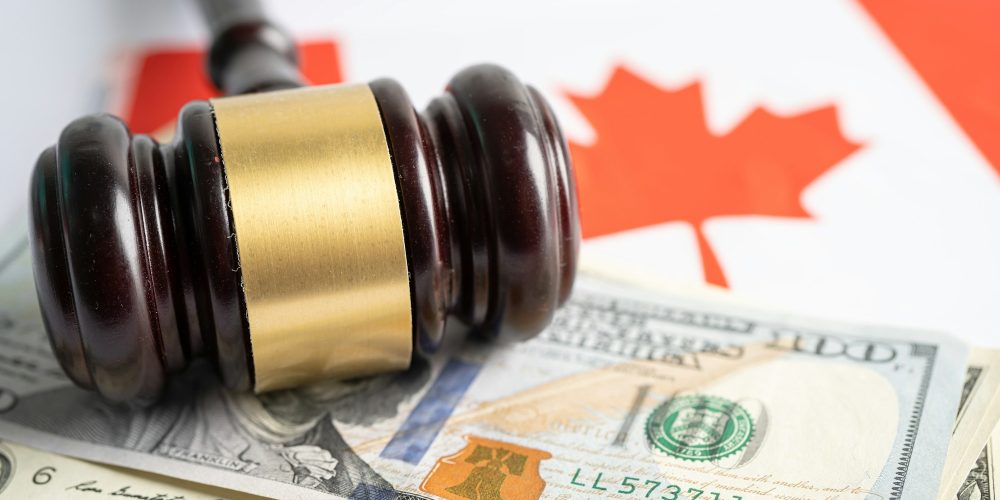 Gavel for judge lawyer and US dollar banknotes on Canada flag, finance concept.