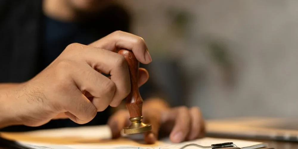 hand-stamping-with-approved-stamp-on-certificate-document-public-paper-at-desk-notary-or-business-qr9zw2ikx66iv59bra4c0dsfi2dos51p3gslj8hci0