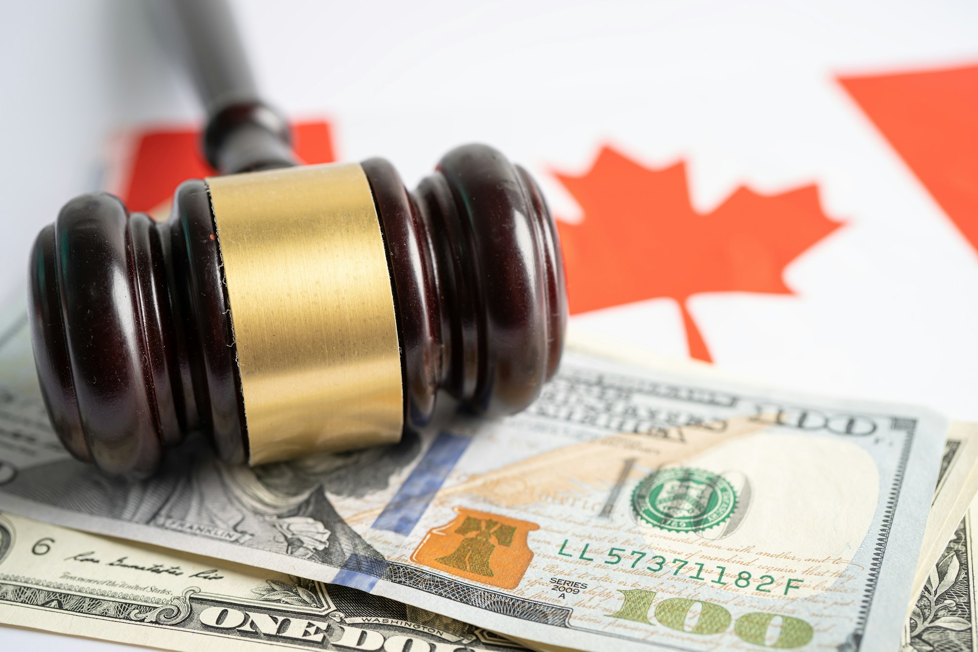 Gavel for judge lawyer and US dollar banknotes on Canada flag, finance concept.